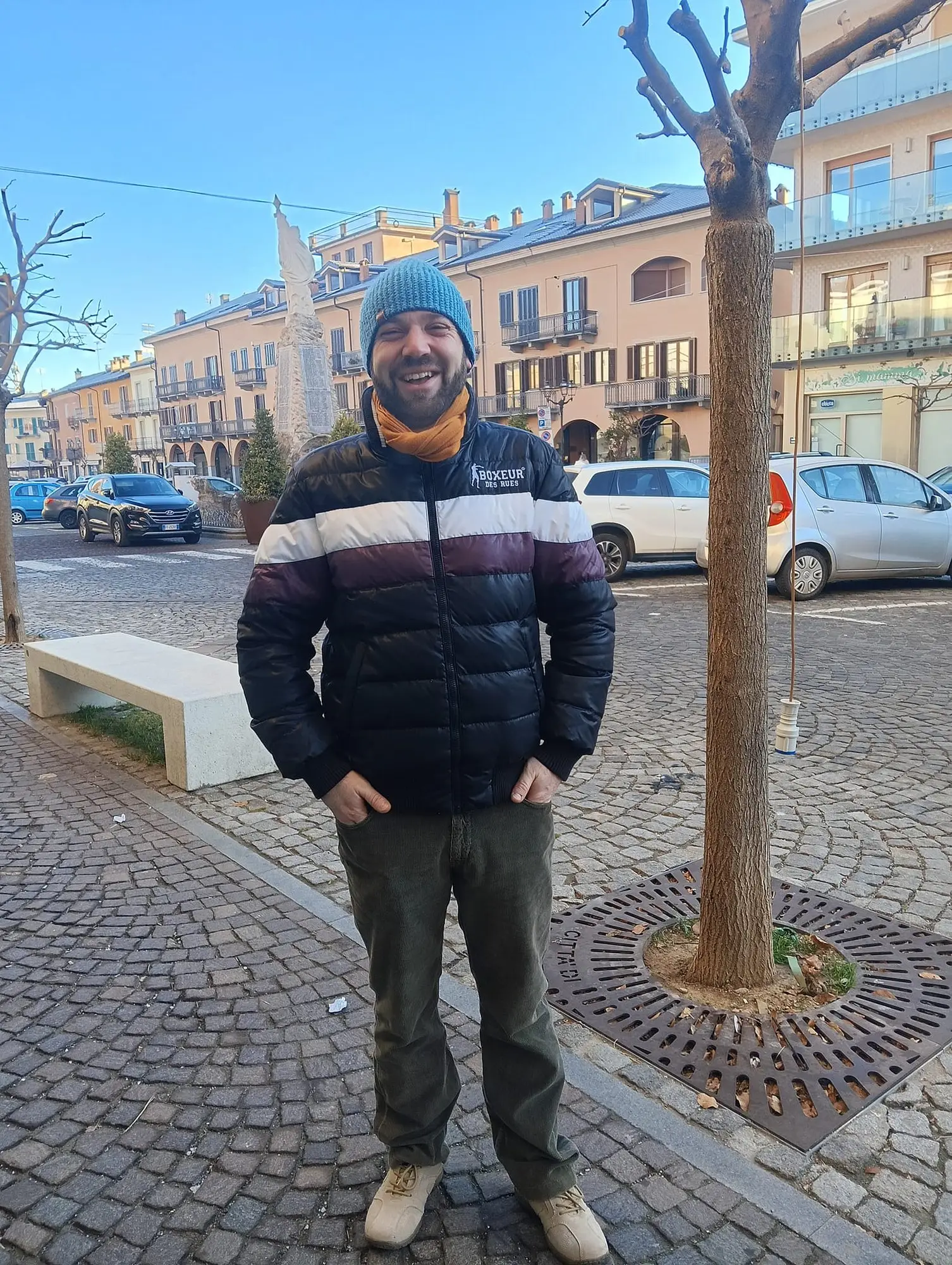 Eros in piazza a Boves, sorridente, con un berretto di lana e il piumino invernale